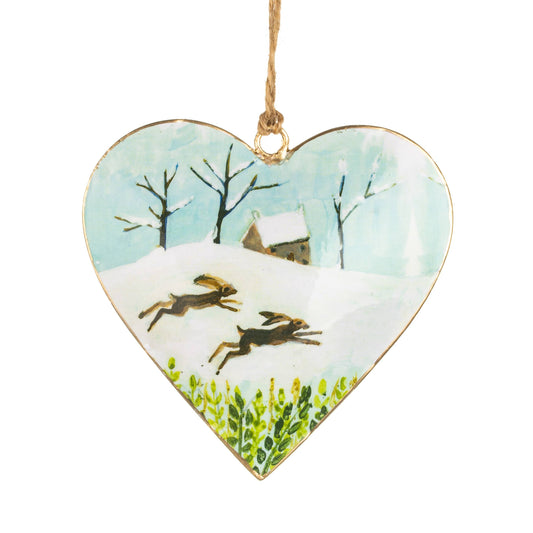 Heart-shaped ornament with winter scene of two hares and a house.